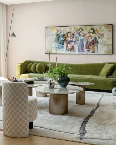 Living room with green velvet sofa, cubist painting, and round marble coffee tables on patterned rug