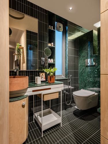 Bathroom with black ribbed tile, green stone wall, terracotta vessel sink and wooden accents