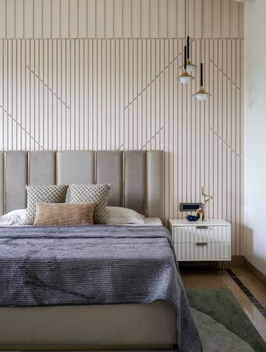 Bedroom with fluted paneled wall, channel-tufted headboard, and twin brass pendant lights