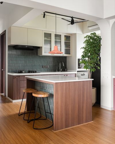 Kitchen with walnut island, teal tiled backsplash, orange pendant light, and tall indoor plant