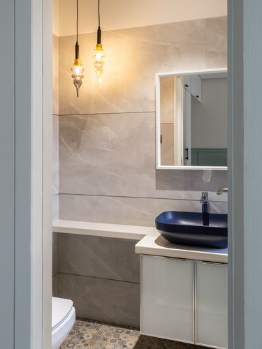 Bathroom viewed through doorway with navy vessel sink, stone-tiled wall, and hanging pendant lights