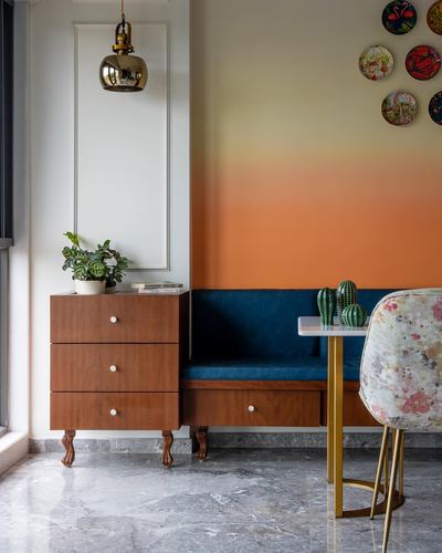 Foyer nook with wooden chest, navy velvet bench, brass pendant, and orange ombré wall