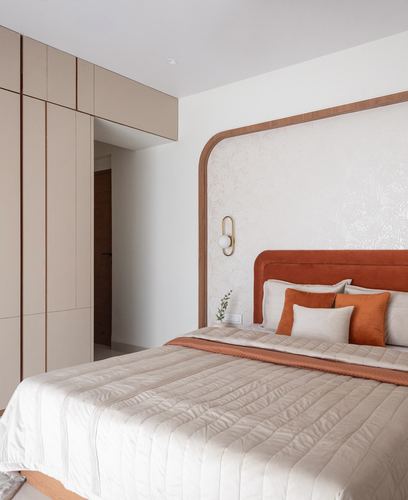 Bedroom with arched terracotta headboard alcove, textured wallpaper, and beige wardrobe