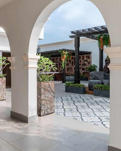 White arched colonnade opening onto a courtyard with patterned tile floor and pergola