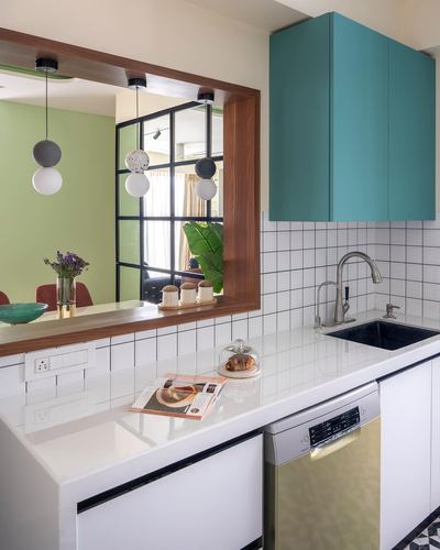 Kitchen with teal cabinet, tiled backsplash and wood-framed opening to dining room beyond