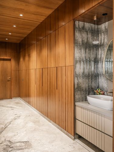 Wood-paneled corridor leading to a bathroom nook with textured tile and vessel sink