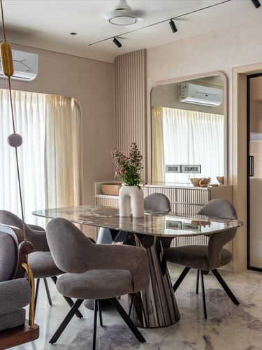 Dining room with oval marble table, grey chairs, and arched mirror reflecting a curtained window