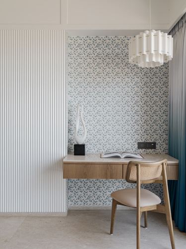 Floating wood desk with cane chair against floral wallpaper and fluted panel wall