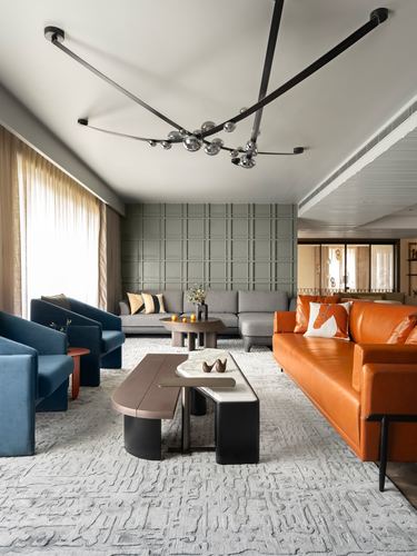 Living room with orange leather sofa, blue armchairs, grey sectional and sculptural ceiling light