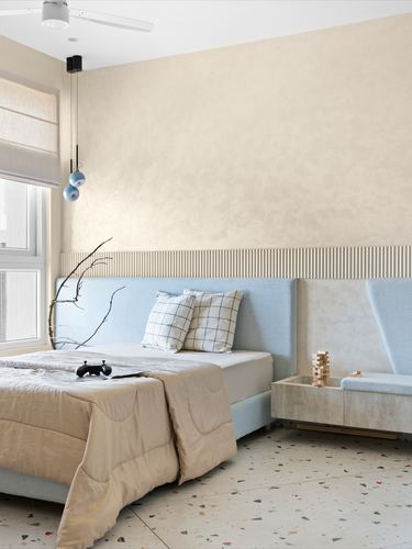 Bedroom with beige plaster wall, blue upholstered headboard, terrazzo floor and pendant lights
