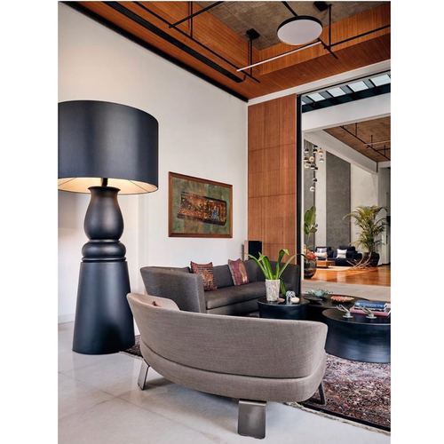 Living room with tall black floor lamp, grey sofa, round black coffee tables, and view through to another lounge area
