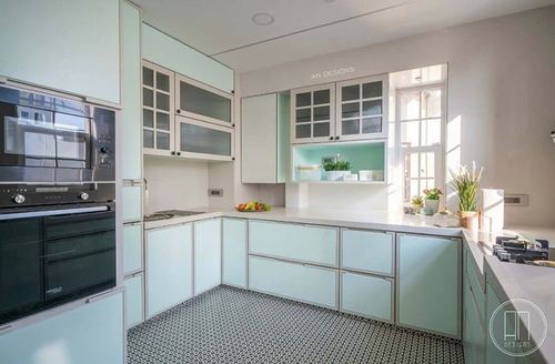 Mint and white L-shaped kitchen with patterned floor tiles and glass-front upper cabinets