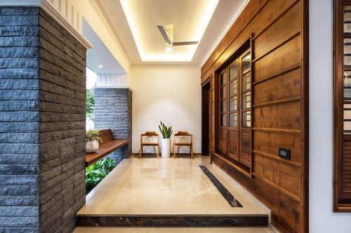 Entrance passage with slate stone wall, wooden louvered doors, marble floor, and cove lighting