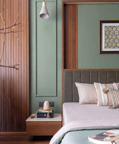 Bedroom corner with fluted wood paneling, sage green wall, framed art, and channel-tufted headboard