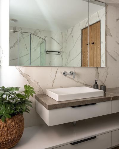 Bathroom with floating vanity, rectangular vessel sink, mirror reflecting shower and wooden cabinet