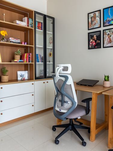 Home study with wooden desk, ergonomic chair, open shelving and family photo wall