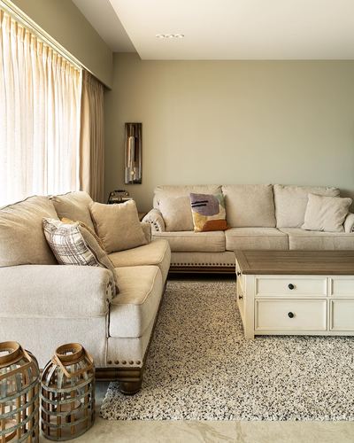 Neutral-toned living room with sectional sofa, wood coffee table, and sheer curtained window