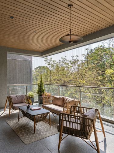Balcony seating with rattan chairs, wood-slat ceiling, and pendant light overlooking greenery