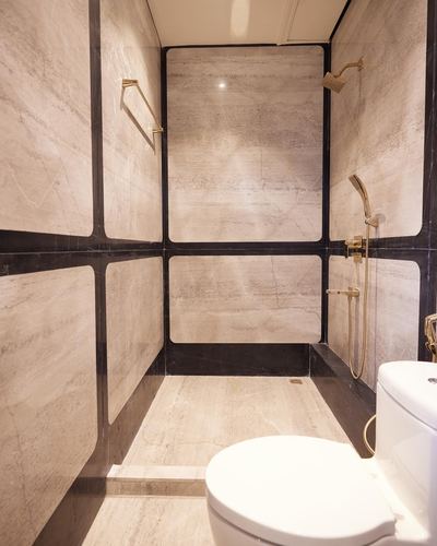 Symmetrical bathroom with veined stone panels framed in black metal and brass fixtures