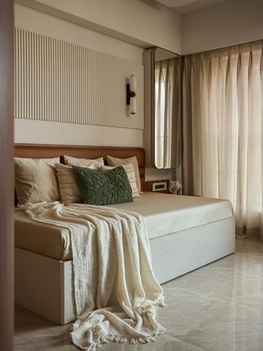 Bedroom with leather headboard, fluted wall panel, round mirror, and draped ivory throw