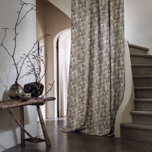 Patterned fabric draped from ceiling beside curved staircase and rustic wooden bench with branches