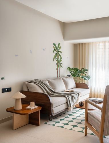 Living room with curved wood-framed sofa, linen throw, indoor plants and geometric green rug near sheer curtains