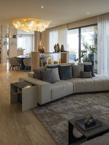 Curved beige sectional in open living room with floral pendant light and dining area beyond