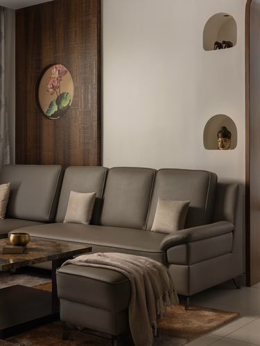 Grey leather sectional sofa facing carved wood wall with round floral art and arched niches