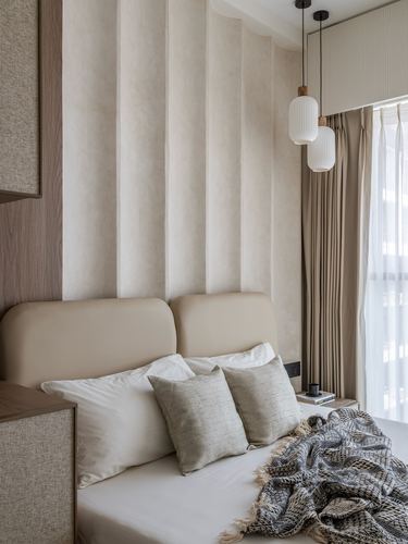 Beige bedroom with fluted fabric headboard wall and layered pendant lights beside curtained window