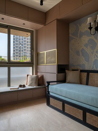 Bedroom nook with window seat, cane daybed, and bird-motif wallpaper wall