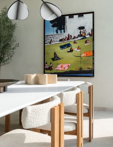 Dining area with boucle chairs, white table, and a large colorful painting on a plaster wall