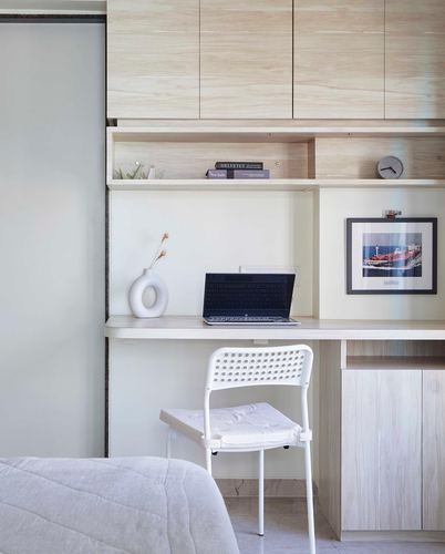 Built-in wood desk nook with laptop, vase, and open shelves above
