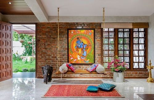 Traditional Kerala living room with brick wall, hanging swing, colorful Krishna painting and red rug