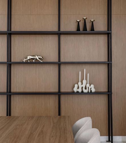 Wood-paneled wall with black metal open shelving holding sculptural decor above a wooden dining table