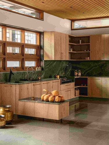 Wood-paneled kitchen with green stone counters, island of coconuts, brass urns, wooden windows letting in light