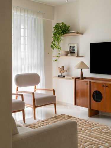 Japandi living room corner with wooden sideboard, TV, floating shelves and cane-armed chair