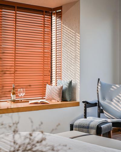 Sunlit window seat with wine and book beside a leather-strapped lounge chair