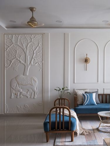 Living room with sculpted plaster cow-and-calf mural, arched niches, and blue wooden sofas.