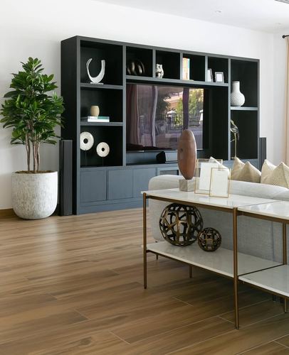 Living room with dark built-in shelving, TV, sofa, and marble console table on wood floor