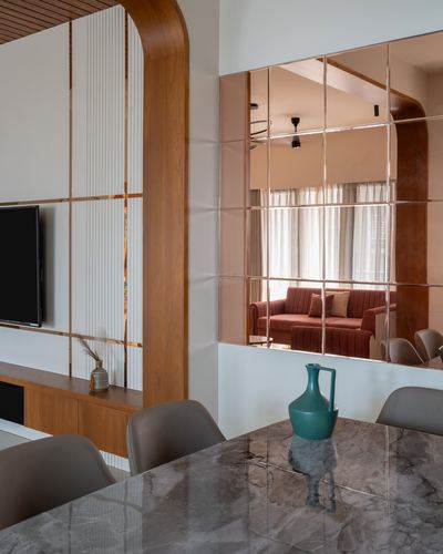 Dining table with marble top and teal vase, mirror panel reflecting living room beyond