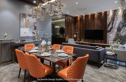 Dining and living area with orange quilted chairs, marble table, and dark wood paneled wall with hidden door
