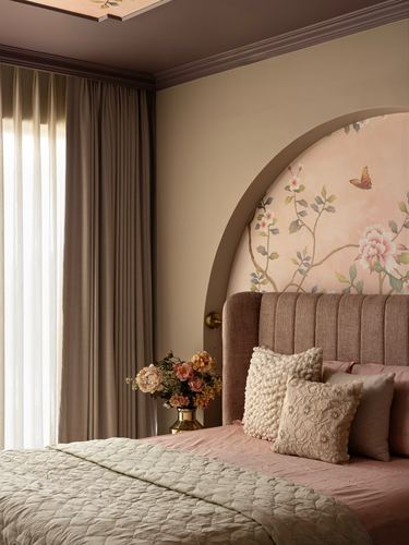 Arched floral mural above channel-tufted pink headboard in soft-lit bedroom