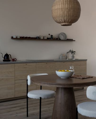 Japandi kitchen and dining nook with round wood table, boucle chairs, and wicker pendant light