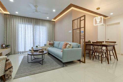 Open living and dining area with blue sofa, round wood coffee tables and slatted wood partition