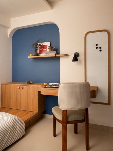 Bedroom corner with blue arched niche, wooden desk, mirror, and striped chair