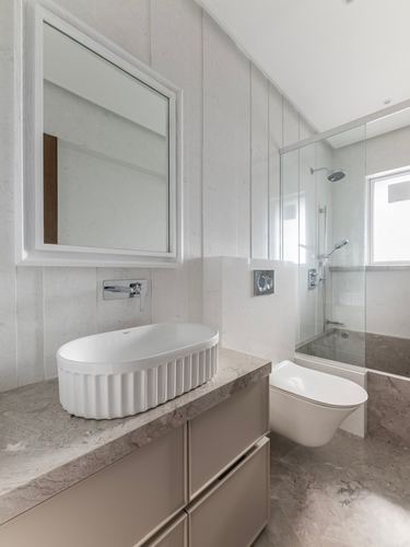 Bathroom with fluted white vessel sink on stone counter, wall-hung toilet, and glass-enclosed shower