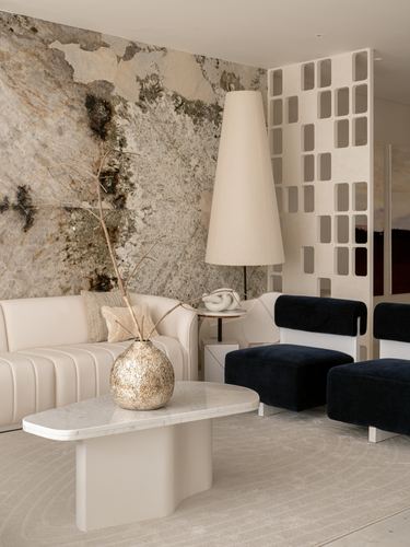 Living room with marble feature wall, cream channel-tufted sofa and navy velvet chairs