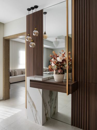 Entryway console with marble base and wood top beneath fluted wood panels and mirror