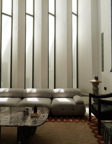 Tall living room with fluted white walls, vertical windows, and a tufted sectional sofa