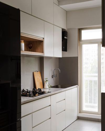 Minimal white galley kitchen with black glossy cabinetry and window overlooking city greenery